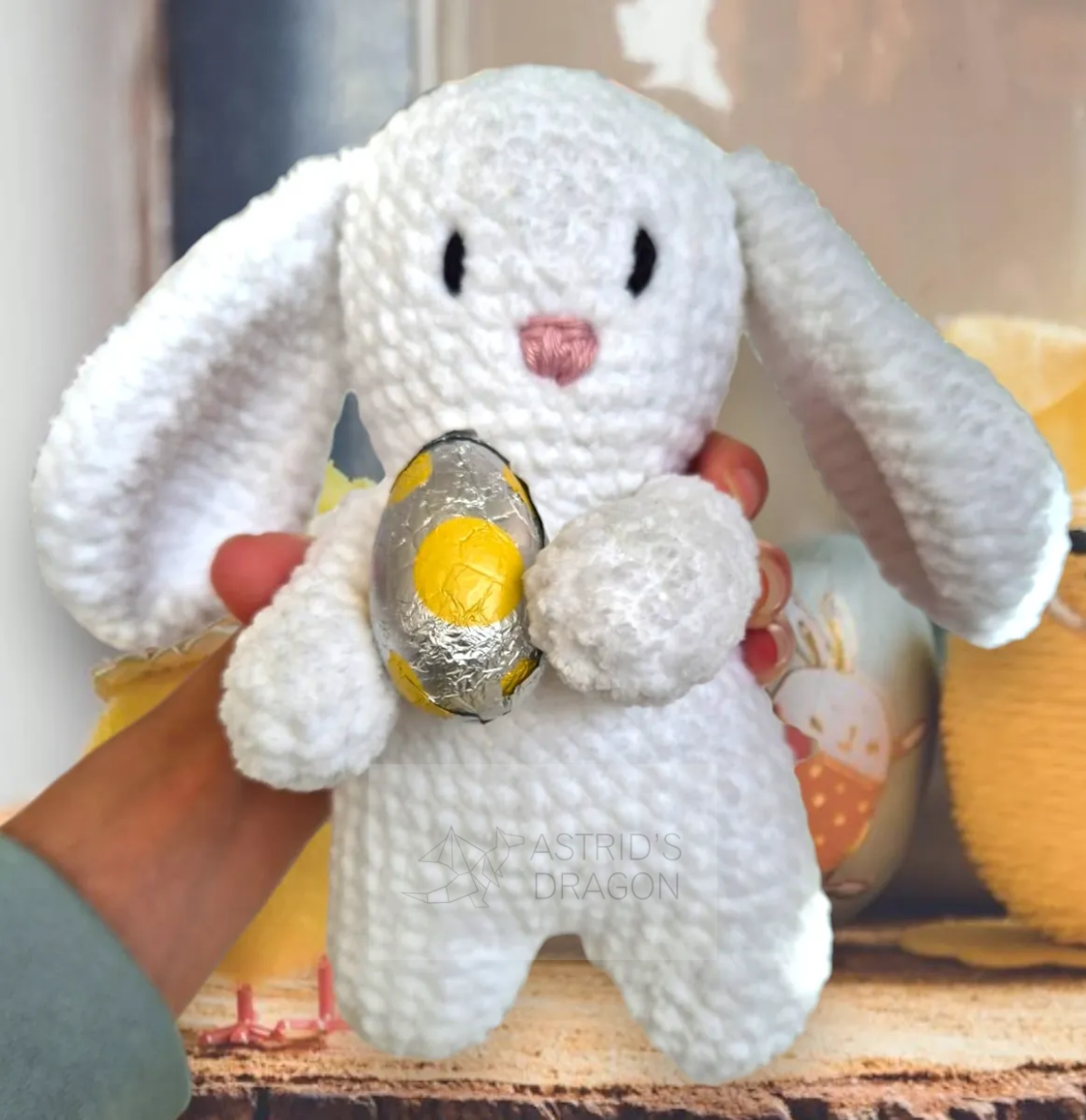 A crocheted white bunny holding an easter egg
