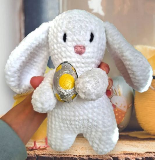 A crocheted white bunny holding an easter egg